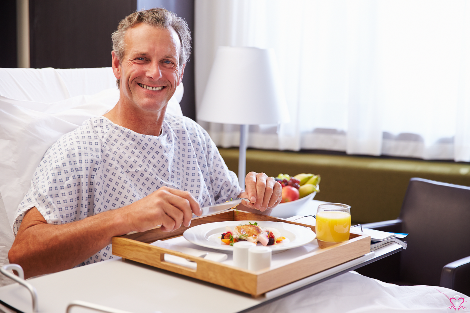 Smiling patient in a hospital bed enjoying a meal.