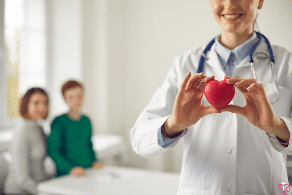 Heart Disease Management - A doctor holding a small red heart, symbolizing heart health, with a family blurred in the background.