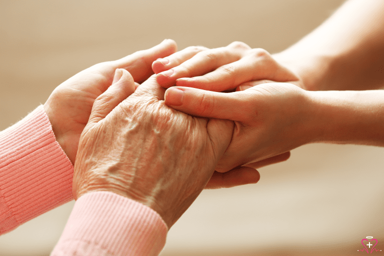 Senior holding a nurse's hand in a hospice setting.