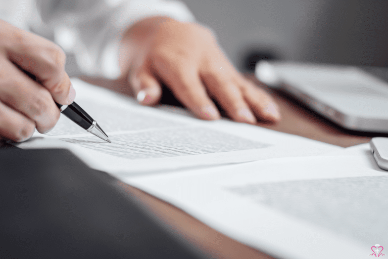 Hands reviewing a paper document at a desk beside a laptop.