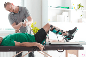 Therapist assisting a patient using a Continuous Passive Motion (CPM) machine.