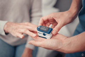 A person using a pulse oximeter on a patient's finger.