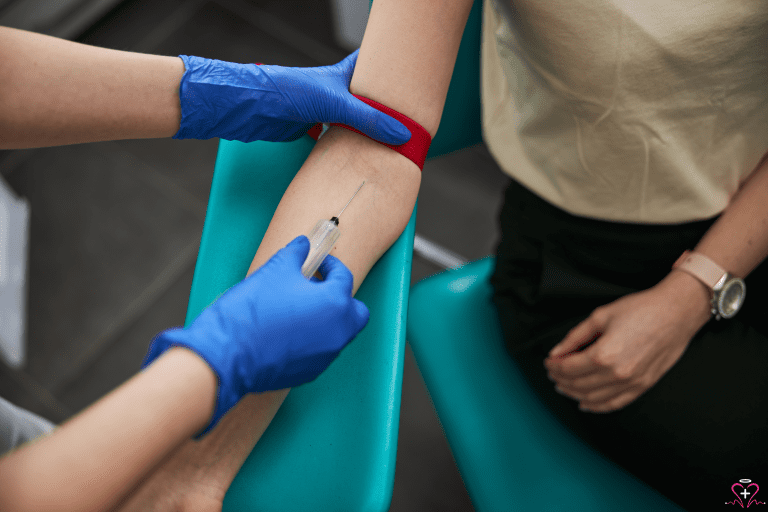 Women's Health Blood Tests - A close-up image of a healthcare professional wearing blue gloves drawing blood from a patient's arm using a syringe. The patient is seated in a chair with a red tourniquet applied to their upper arm.