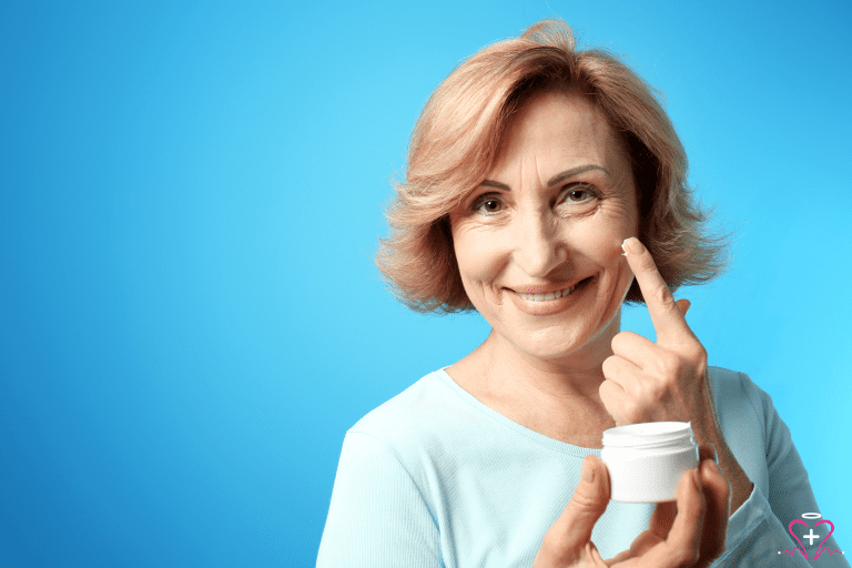 Senior woman applying barrier cream to her face with a blue background.