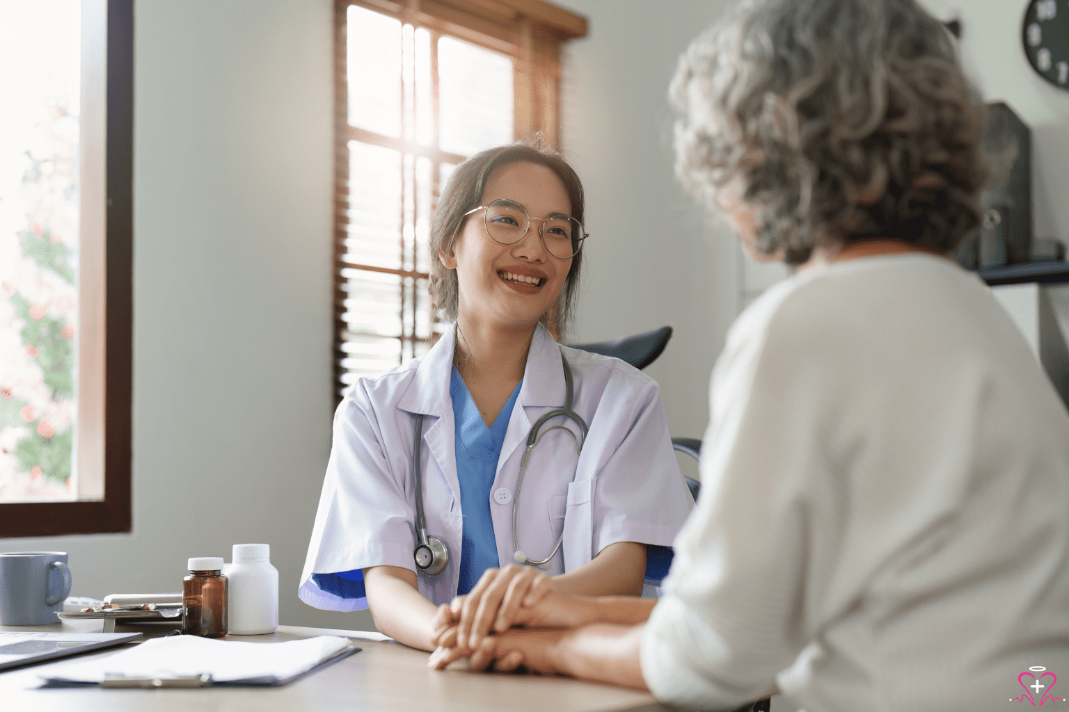 The Importance of Primary Care Physicians - Doctor smiling while holding the hands of an elderly patient