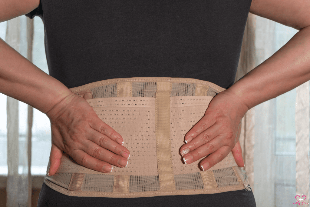 Back Brace - A close-up image of a person wearing a beige back brace for support, with hands placed on the lower back.