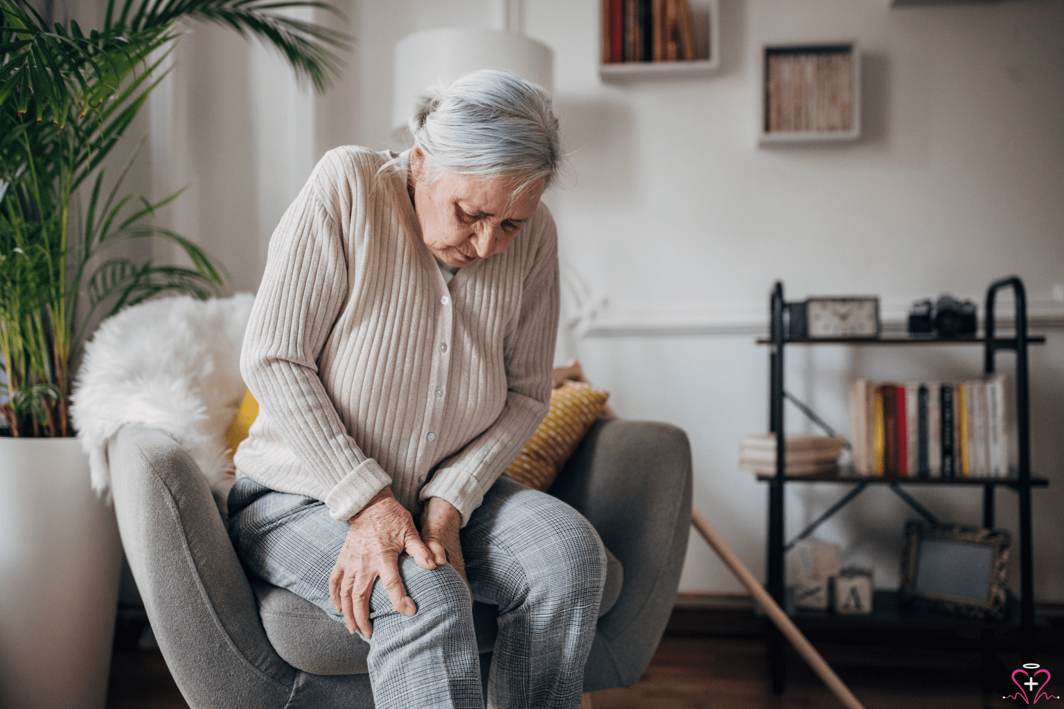 Pain Management: An elderly woman sitting in a chair, holding her knee in pain.