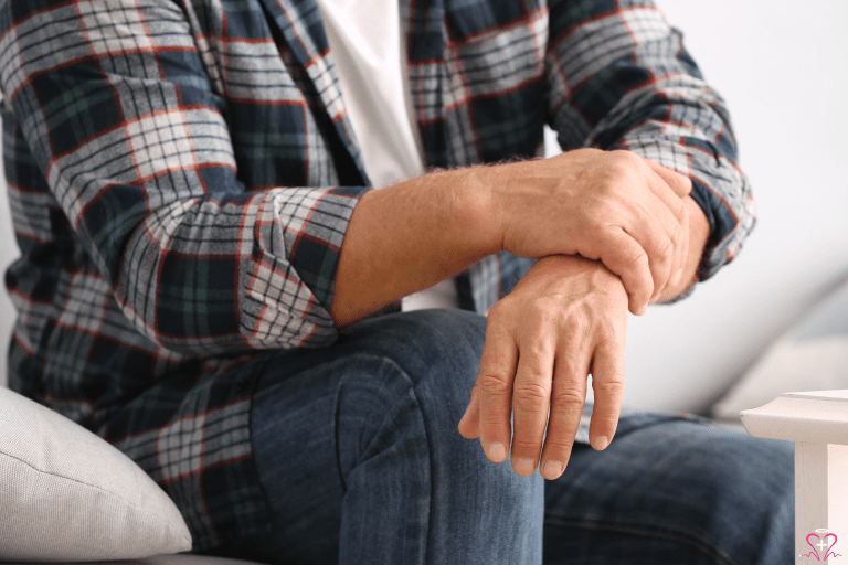 Symptom Management - Close-up of an older man's hands, one resting on the other, as he sits in a relaxed position.