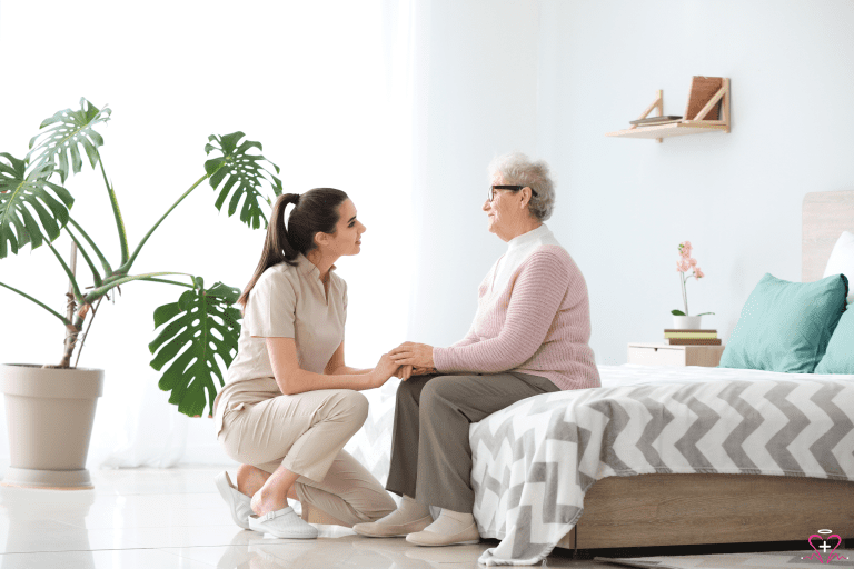 Senior Placement Service: Caregiver holding hands with a senior woman sitting on a bed.