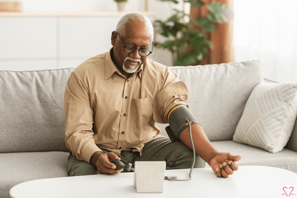 Blood Pressure Monitors - An elderly man sitting on a couch using a blood pressure monitor to check his blood pressure at home.