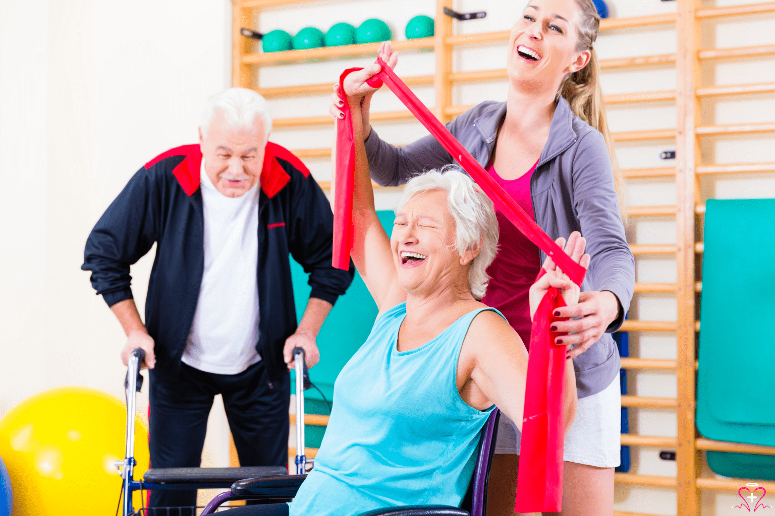 The Benefits of Physical Rehabilitation Therapy - Physical therapist assisting an elderly woman with resistance band exercises while another elderly man watches