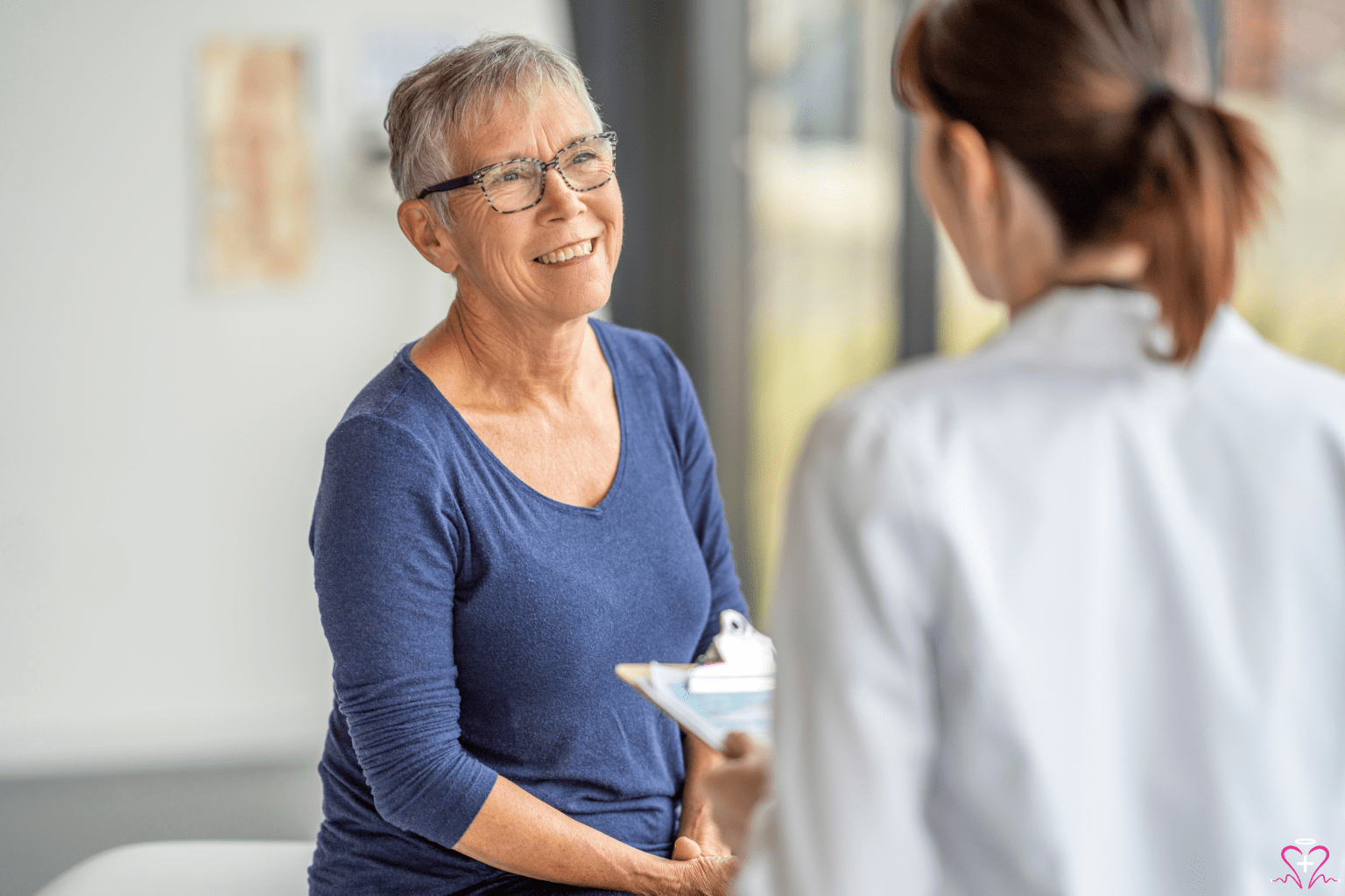 Importance of Regular Routine Check-ups - An elderly woman smiling during a routine check-up with a healthcare provider.