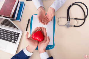 Routine Check-ups - A doctor and a patient during a routine check-up, with the doctor holding a red heart model.