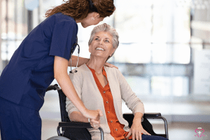 Home Safety Modifications -Nurse assisting a senior woman in a wheelchair, both smiling warmly.