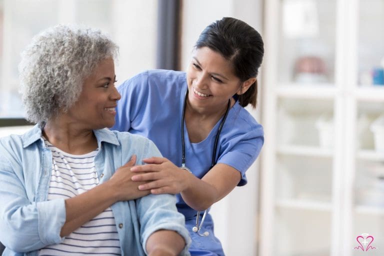 A nurse in blue scrubs providing support to a smiling senior woman, showcasing senior healthcare and support