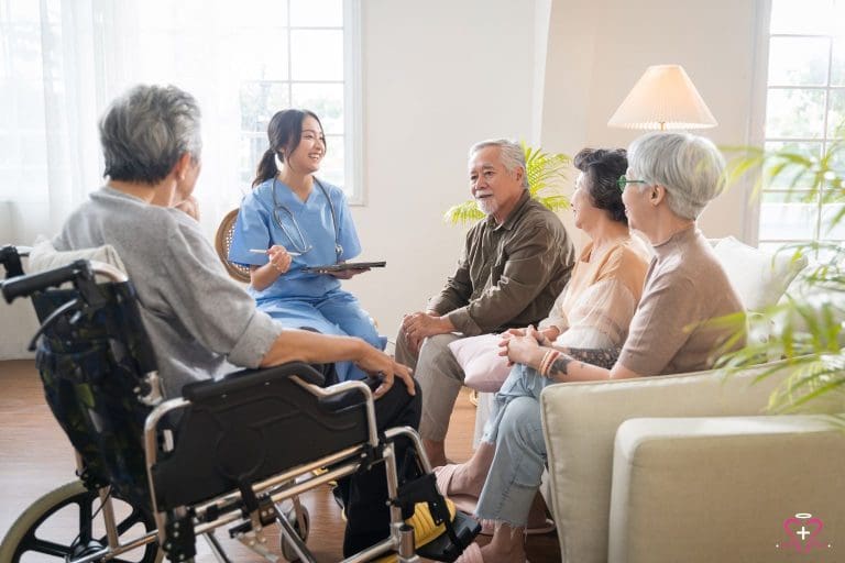 Senior Healthcare professional in blue scrubs consulting with a group of seniors, including a man in a wheelchair, in a bright, comfortable living