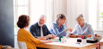 Group of seniors talking and engaging in activities around a table, representing the Senior Center Liaison role and community engagement for older adults