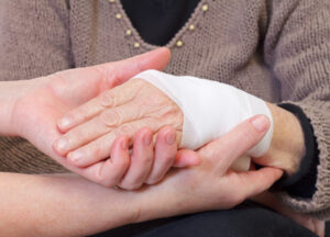 Healthcare professional bandaging an elderly patient’s hand, representing chronic wound care for seniors, infection prevention, and compassionate medical support.