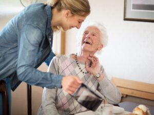 Caregiver pouring coffee for a smiling senior woman – adult day care placement for seniors requiring supervision in Los Angeles.
