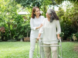 Caregiver assisting senior woman with a walker outdoors – home health placement for seniors with medical needs in Los Angeles.