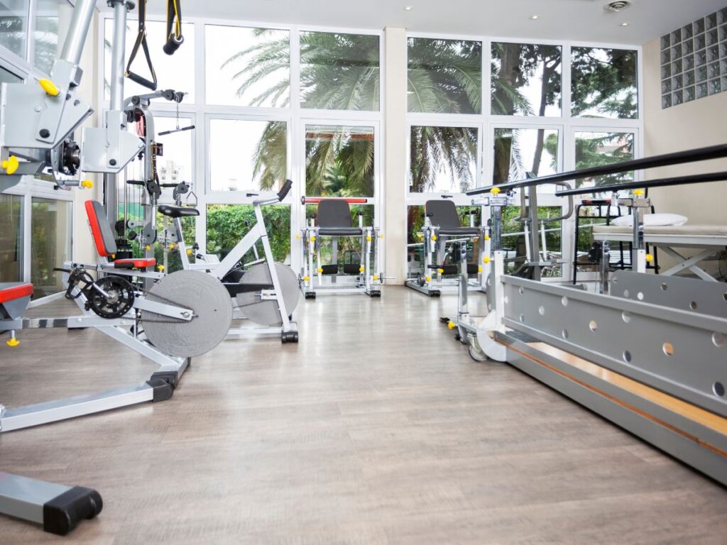 Senior man using a parallel bar for physical therapy – senior rehab center placement after hospital stay and recovery support in Los Angeles.