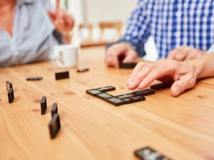 Caregiver playing dominoes with a senior – subacute senior care placement for complex needs and rehabilitation support in Los Angeles.