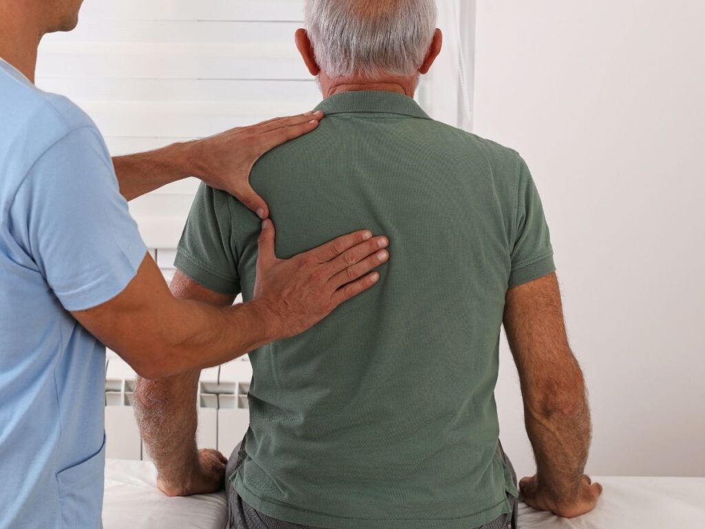 Doctor assisting senior man with back therapy – back pain treatment and rehabilitation for seniors in Los Angeles.