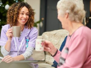 Smiling caregiver sharing tea with a senior woman – compassionate in-home care services for seniors in Encino, Los Angeles.