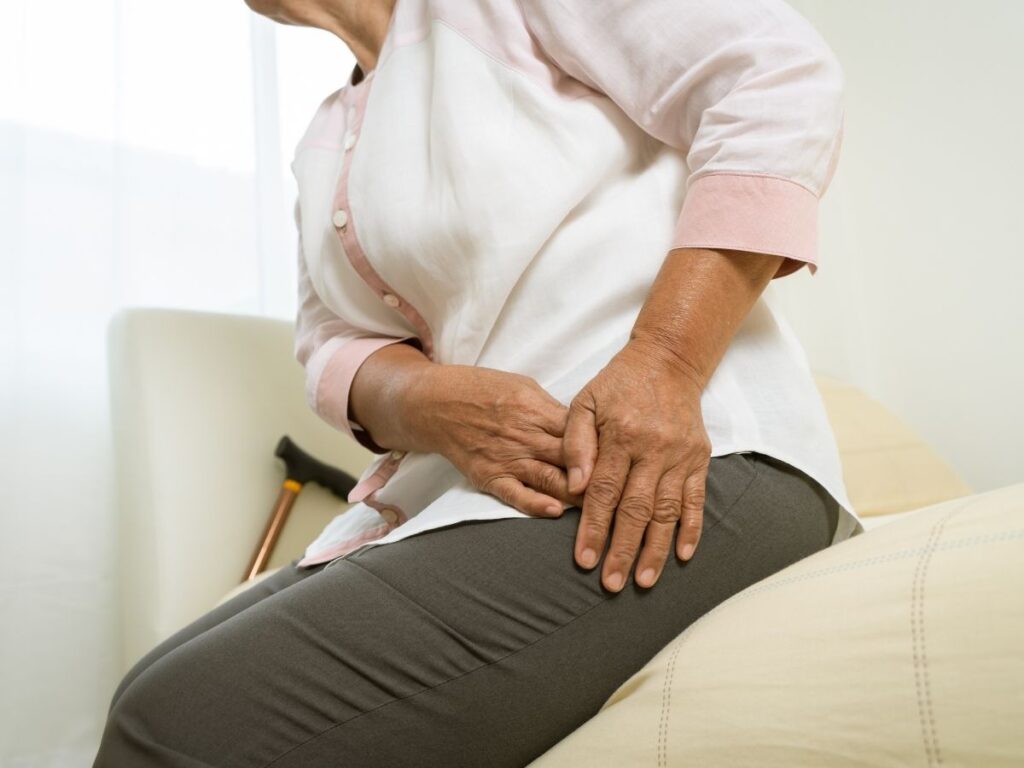 Senior woman holding her hip while reviewing bursitis and joint comfort support.