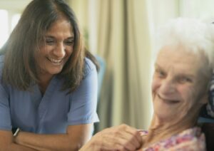 Smiling caregiver with senior at home, illustrating how to choose a home health aide in Los Angeles