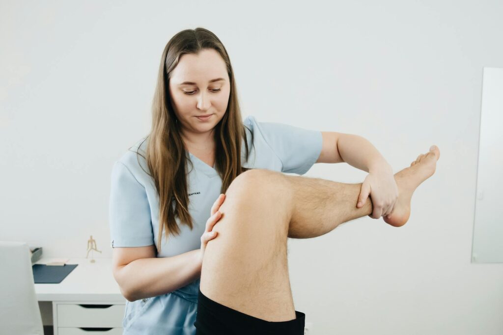 A physiotherapist assisting a patient's leg therapy session indoors, focusing on rehabilitation.