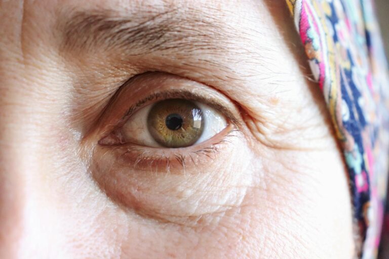 Primer plano detallado del ojo de una anciana que lleva un pañuelo colorido en la cabeza.