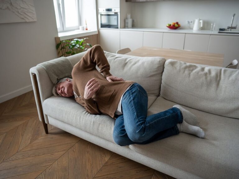 一位老年男子因背部不适休息，同时查看神经压迫和脊柱支撑方案。