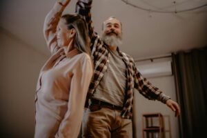 An elderly couple enjoying a dance together in their cozy living room, showcasing love and companionship.