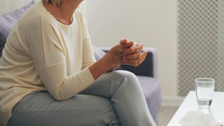 Una anciana sentada pensativa en una sala de terapia.