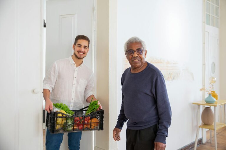 Meal program volunteer sharing fresh groceries and senior-support information with an older adult in Los Angeles.