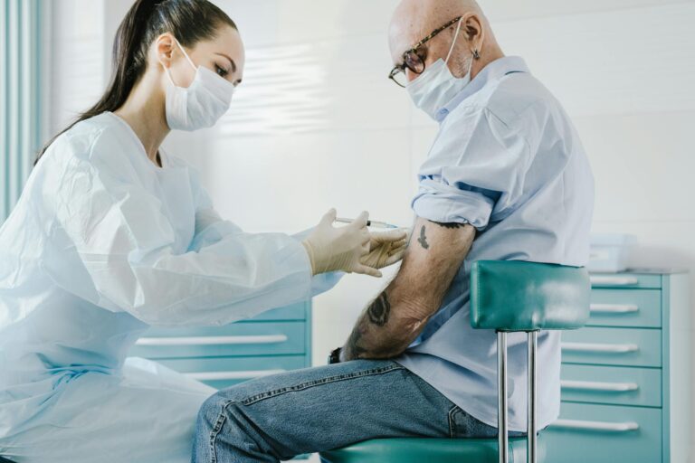 Profesional sanitario administrando una inyección de vacuna a un paciente en un entorno clínico.