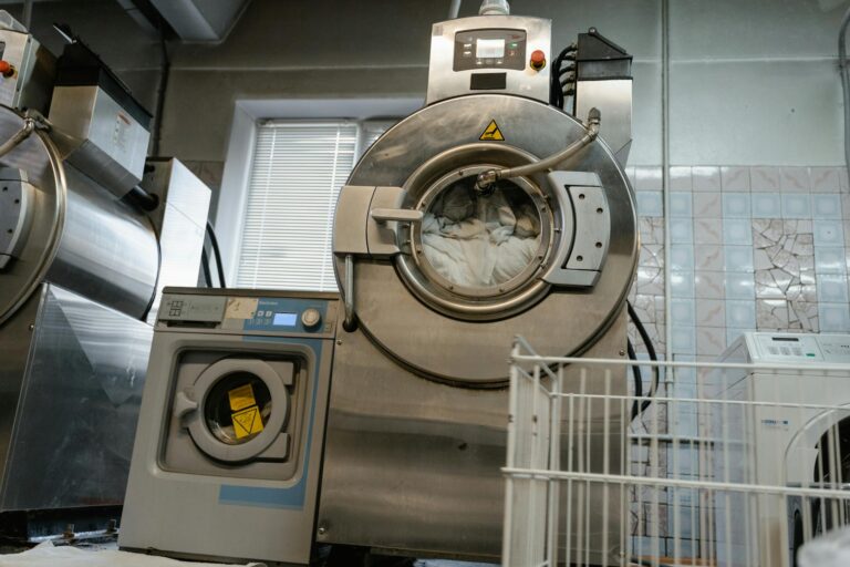 Large industrial laundry machines in a service room environment.