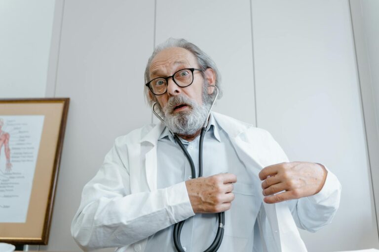 Surprised elderly doctor wearing lab coat and stethoscope indoors.