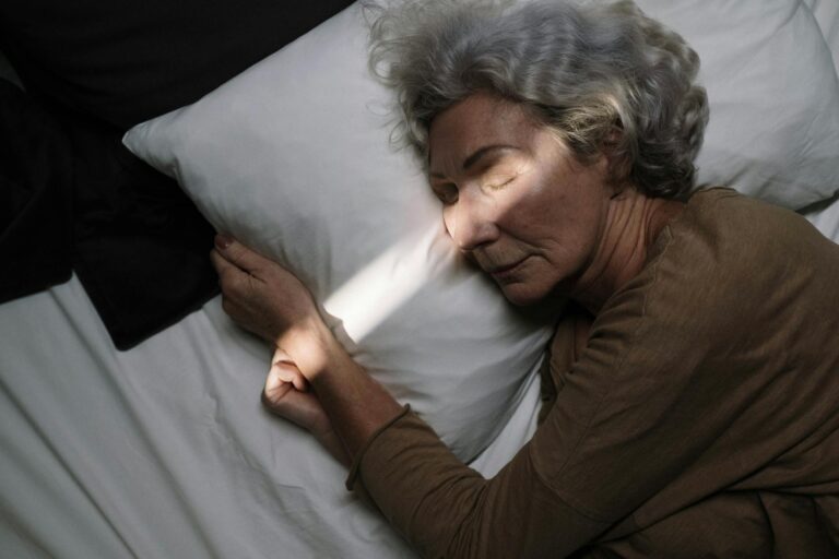 Un momento de serenidad: una anciana duerme plácidamente en una cama con iluminación tenue.