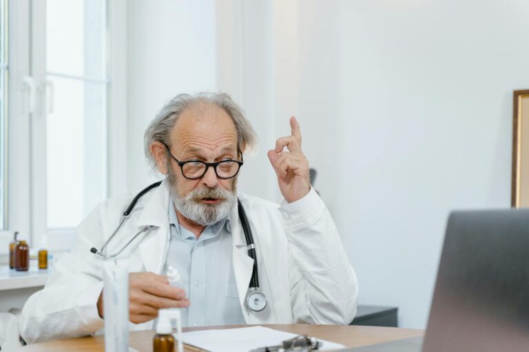 Médico sénior con bata blanca realizando una consulta en línea. Profesional de la salud utilizando la tecnología para la atención médica.