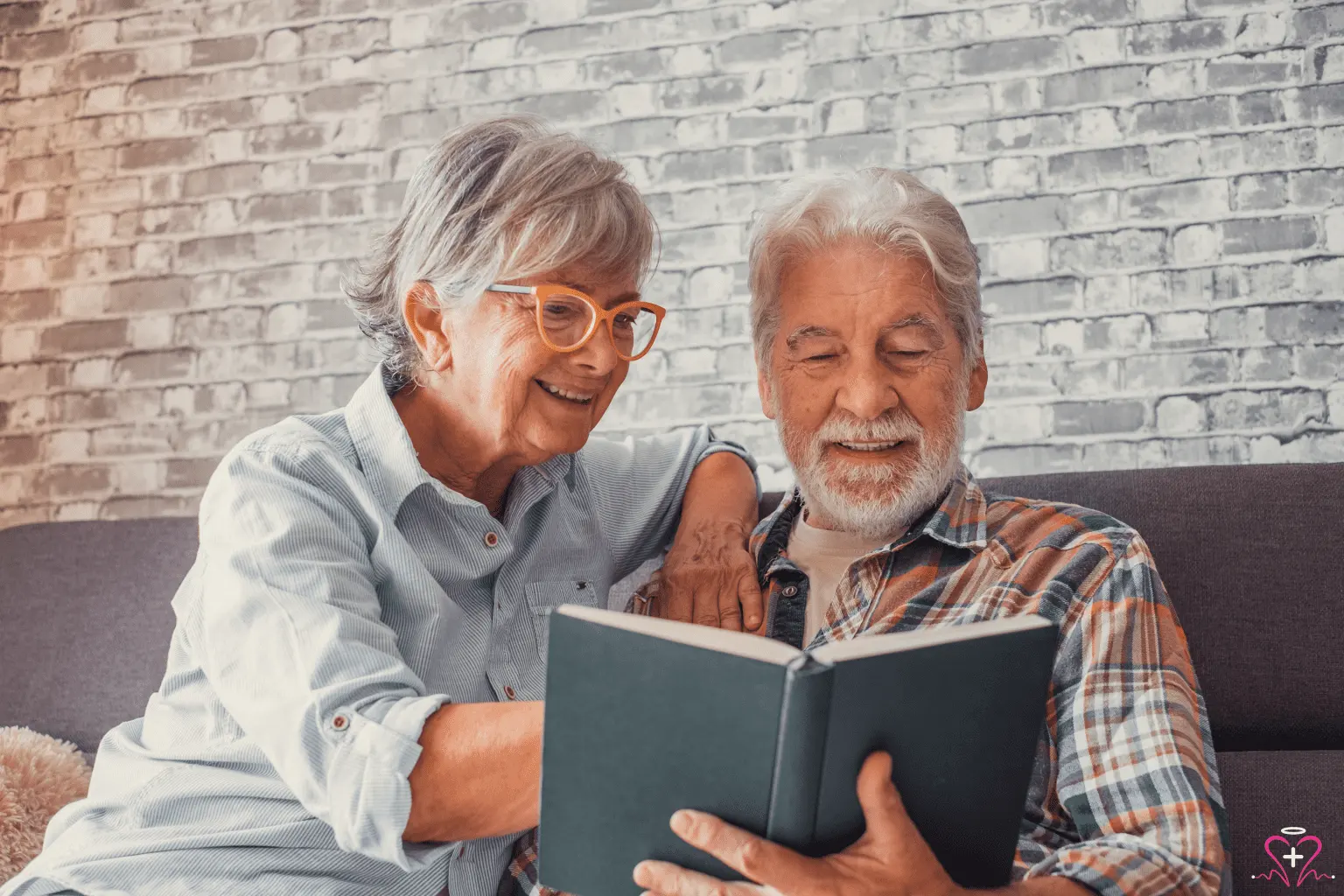 Happy senior couple reading together at home, representing senior learning, companionship, and wellness support from All Seniors Foundation.