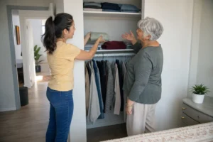 Older adult and family helper arranging a mid-height closet shelf in a Los Angeles home