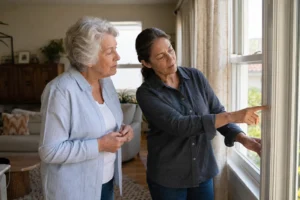 Older adult and a home energy professional examining a window frame together